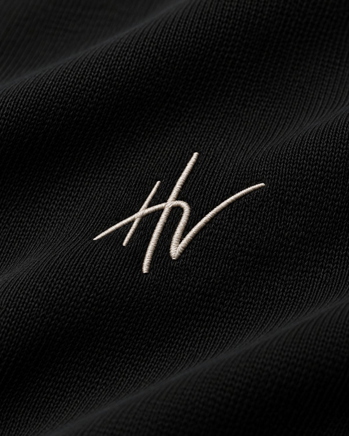 Close-up of the HV monogram embroidered on the black tee